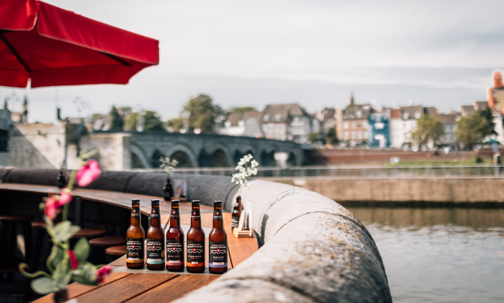 Biertjes van Stadsbrouwerij Maastricht aan de Maas met uitzicht op de Servaasbrug